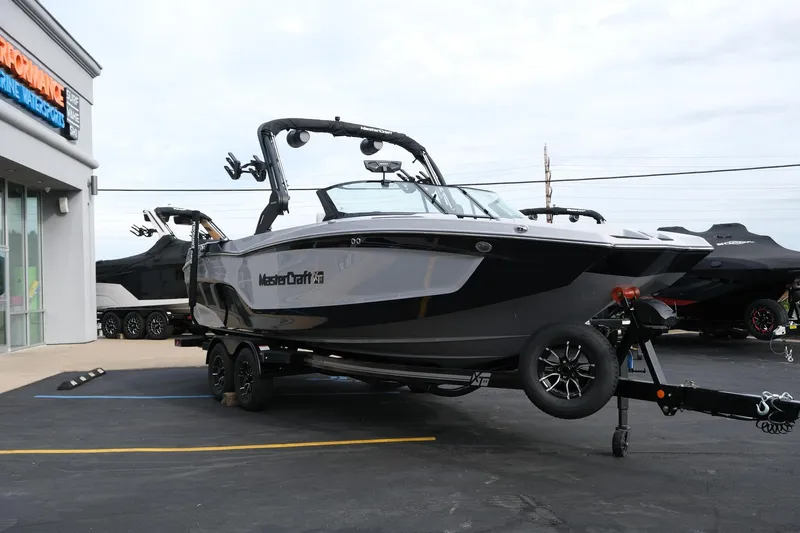 Slide: The Image of 2026 MasterCraft XT24 boat on trailer at dealership parking lot. - 9