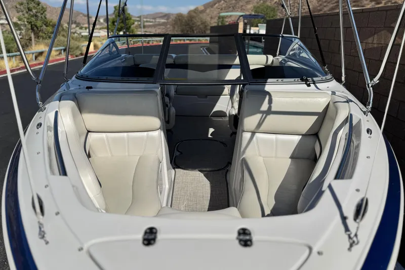 Slide: The Image of 2010 Four Winns H210 boat interior with white leather seats and open windshield. - 10