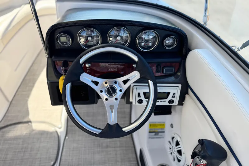 Slide: The Image of Steering wheel and dashboard of 2010 Four Winns H210 boat, featuring gauges and controls. - 22