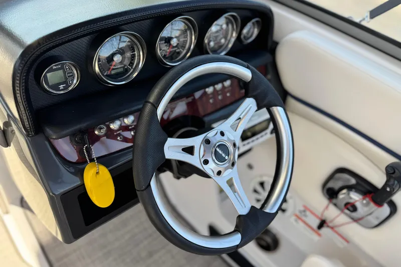 Slide: The Image of Steering wheel and dashboard of 2010 Four Winns H210 boat, featuring gauges and controls. - 23