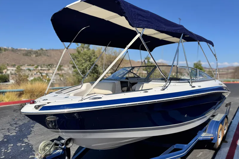 Slide: The Image of 2010 Four Winns H210 boat with blue canopy on a trailer, parked outdoors. - 3