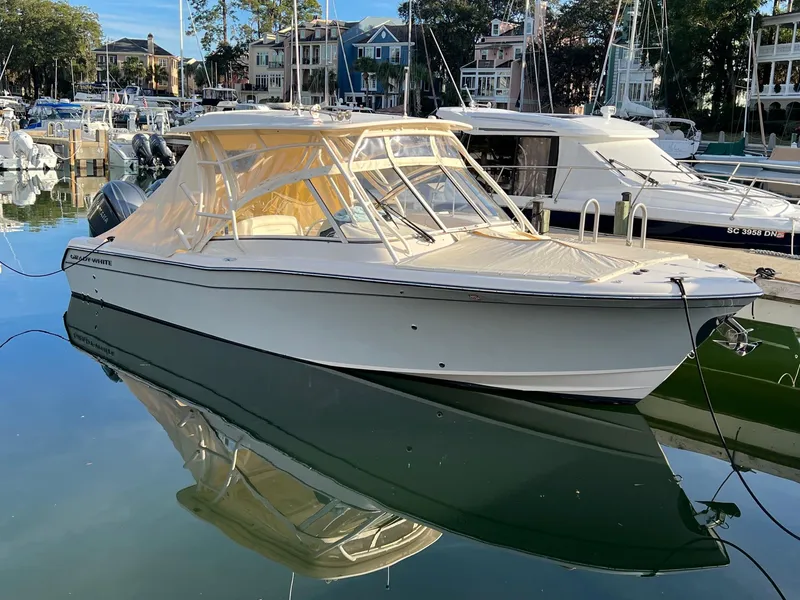 The Image of 2021 Grady-White Freedom 285 boat docked in a marina, reflecting on calm water. - 0
