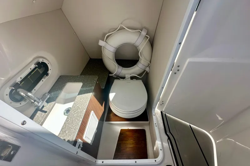 Slide: The Image of 2019 Four Winns HD270 OB boat bathroom with sink, toilet, and life preserver. - 11