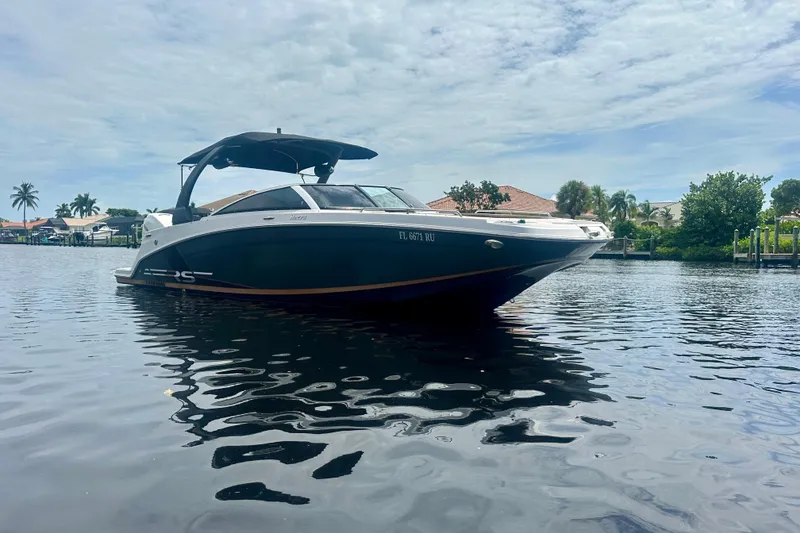 Slide: The Image of 2019 Four Winns HD270 OB boat on calm water, under a partly cloudy sky. - 2