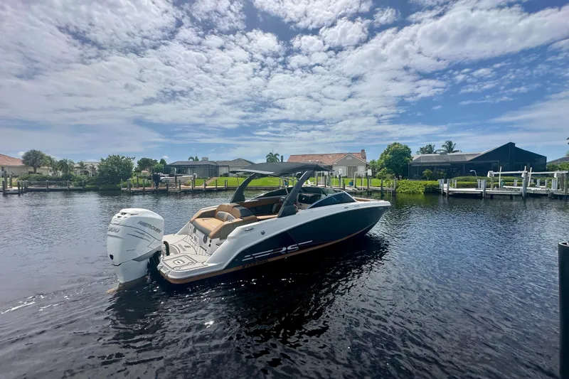Slide: The Image of 2019 Four Winns HD270 OB boat on a sunny waterfront, featuring a sleek design. - 3