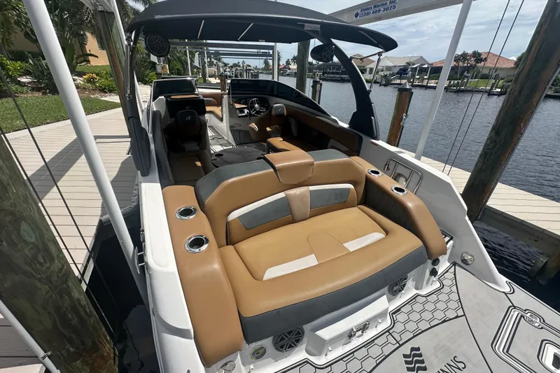 Slide: The Image of 2019 Four Winns HD270 OB boat interior with tan seating, docked by a waterfront. - 4