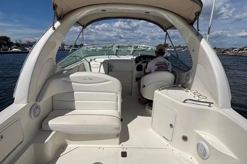 Slide: The Image of 2003 Sea Ray 280 Sundancer boat interior with seating and helm, docked on a sunny day. - 11
