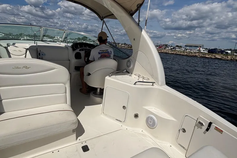 Slide: The Image of 2003 Sea Ray 280 Sundancer boat interior with seating and helm, cruising on water. - 13