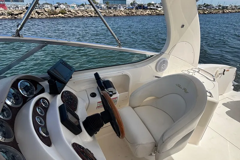 Slide: The Image of 2003 Sea Ray 280 Sundancer helm with steering wheel and control panel, docked by the water. - 15