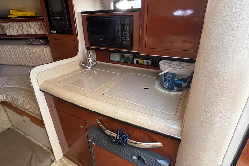 Slide: The Image of 2003 Sea Ray 280 Sundancer interior kitchenette with sink, microwave, and storage. - 20