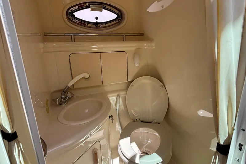 Slide: The Image of 2003 Sea Ray 280 Sundancer bathroom with sink, toilet, and porthole window. - 26