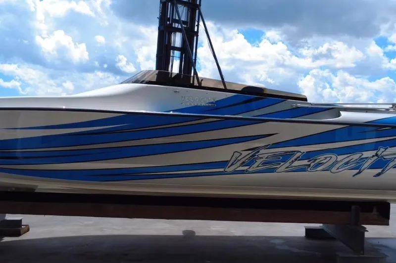 Slide: The Image of 2021 Velocity 290sc speedboat with blue stripes against a cloudy sky backdrop. - 8