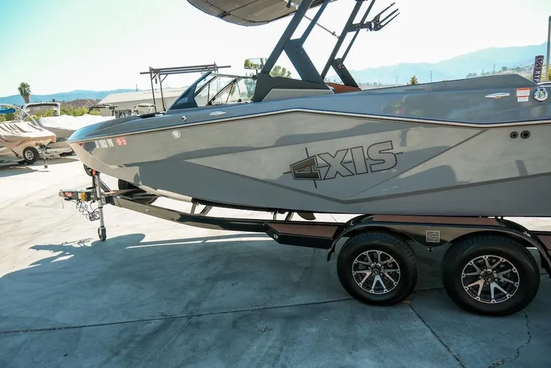 Slide: The Image of 2024 Axis T220 boat on trailer, sleek gray design, parked outdoors. - 12