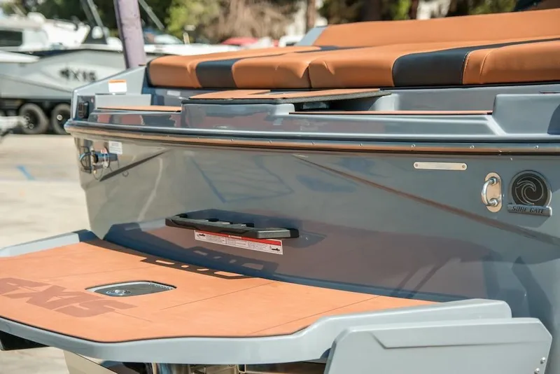 Slide: The Image of 2024 Axis T220 boat rear view with brown seating and Surf Gate feature. - 6