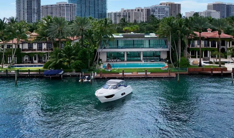 Slide: The Image of Luxury yacht Absolute 40, 2014 model, cruising near waterfront mansion with palm trees and modern architecture. - 11