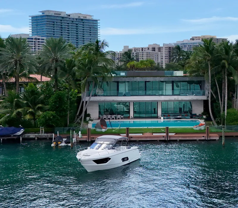 Slide: The Image of Luxurious Absolute 40 yacht near modern waterfront mansion, surrounded by palm trees and cityscape. - 16