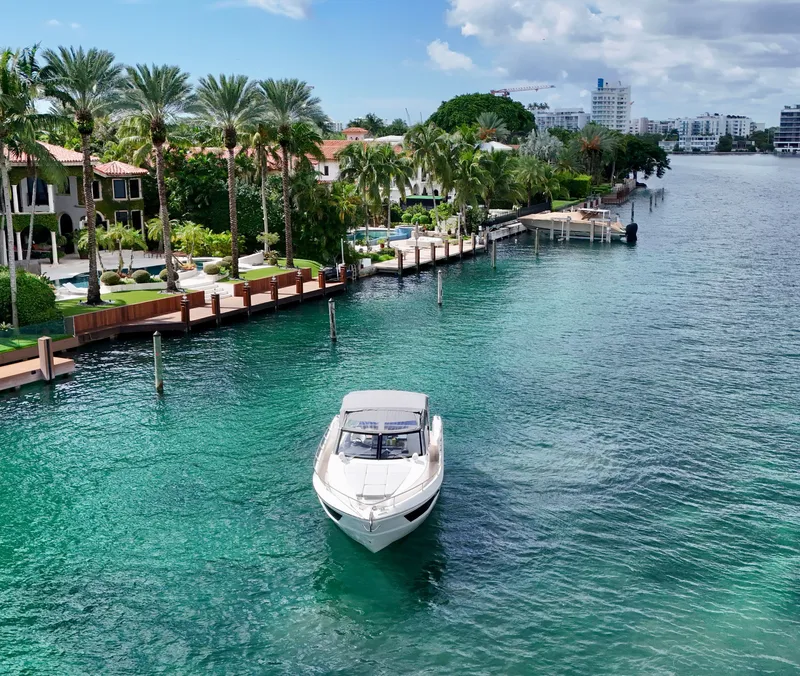 Slide: The Image of Luxury yacht cruising near waterfront homes, surrounded by palm trees and clear blue water. - 2