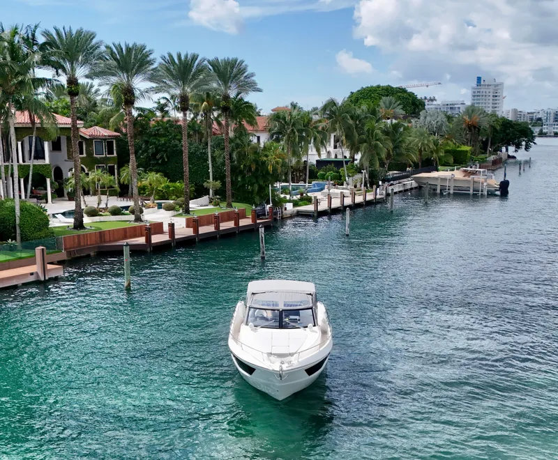 Slide: The Image of Luxury yacht Absolute 40 cruising near waterfront homes, surrounded by palm trees and clear blue water. - 3