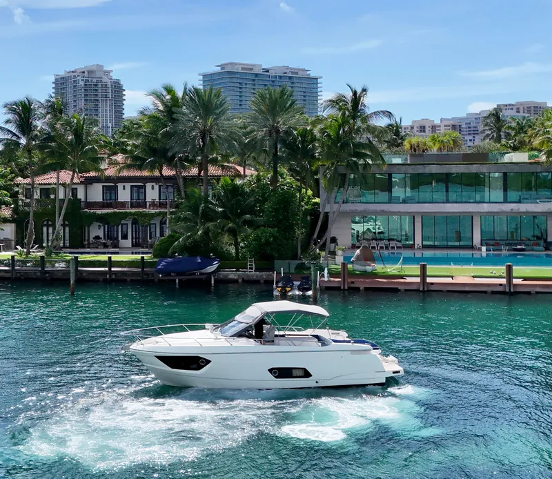Slide: The Image of Luxury Absolute 40 yacht cruising near waterfront homes, surrounded by palm trees and modern architecture. - 35