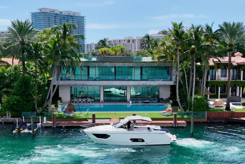 Slide: The Image of Luxury yacht Absolute 40 cruising by a modern waterfront mansion, surrounded by palm trees. - 37