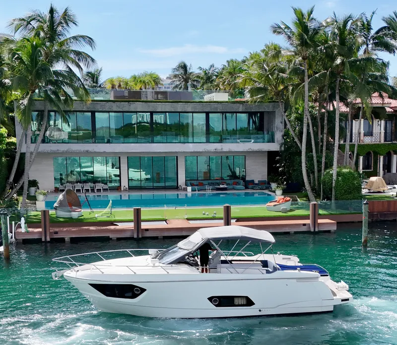 Slide: The Image of Luxury yacht Absolute 40 cruising by a modern waterfront villa with palm trees. - 38