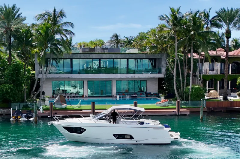 Slide: The Image of Luxury yacht Absolute 40 cruising near modern waterfront mansion, surrounded by palm trees. - 39