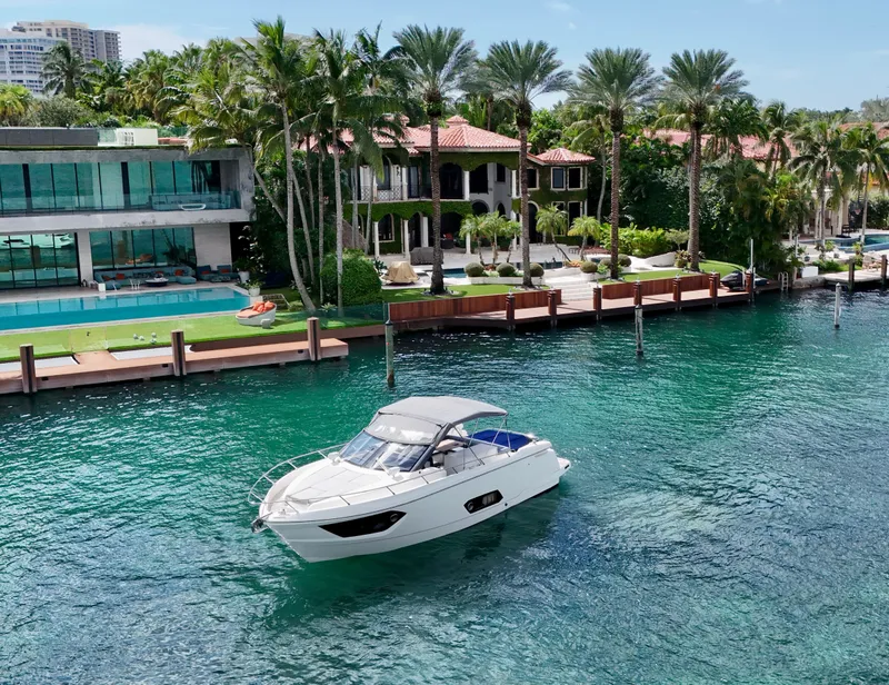 Slide: The Image of Luxurious Absolute 40 yacht cruising near waterfront mansions, surrounded by palm trees and clear blue water. - 4