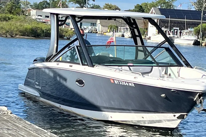 Slide: The Image of 2020 Chaparral 280 OSX boat on water near dock, American flag visible. - 10