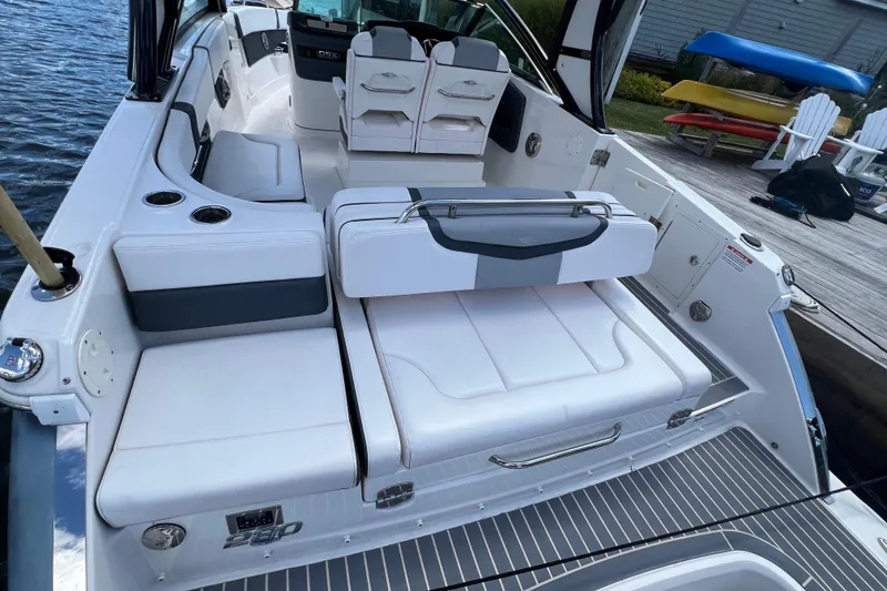 Slide: The Image of 2020 Chaparral 280 OSX boat interior with white seating and cup holders by the water. - 12