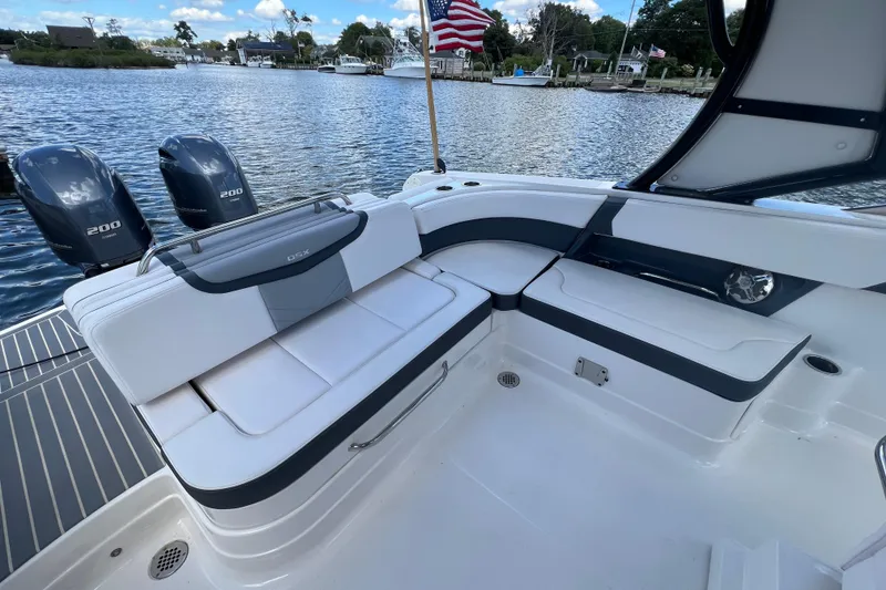Slide: The Image of 2020 Chaparral 280 OSX boat interior with seating and dual outboard engines on a scenic waterway. - 13
