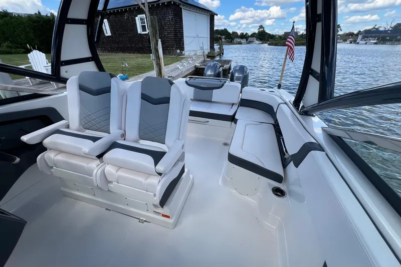 Slide: The Image of 2020 Chaparral 280 OSX boat interior with seating, docked by a serene lake. - 15