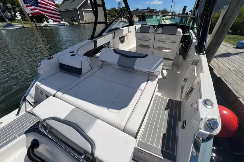Slide: The Image of 2020 Chaparral 280 OSX boat interior with seating, docked by a waterfront. - 23