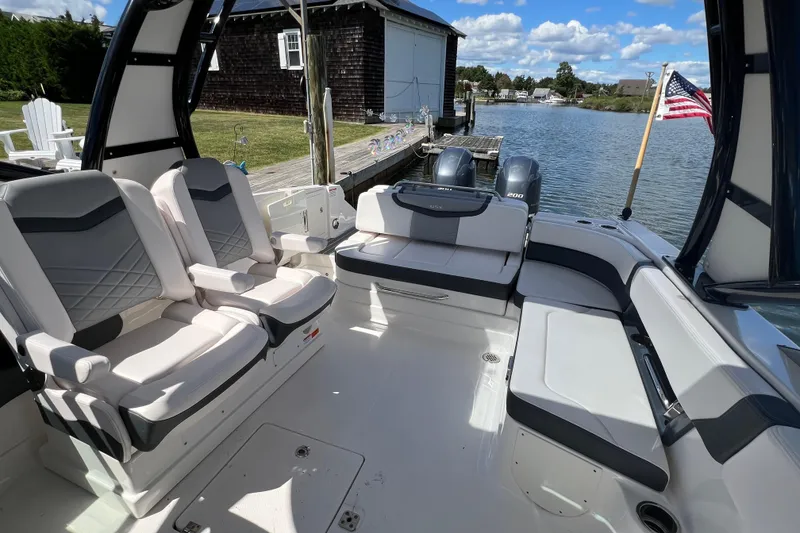 Slide: The Image of 2020 Chaparral 280 OSX boat interior with seating, docked by a scenic waterfront. - 27