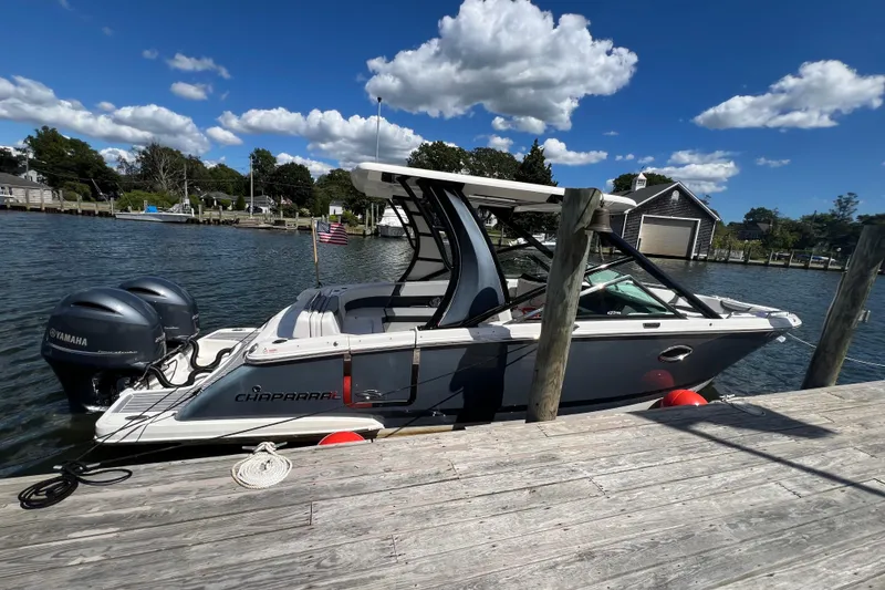 Slide: The Image of 2020 Chaparral 280 OSX boat docked by a wooden pier under a clear blue sky. - 38