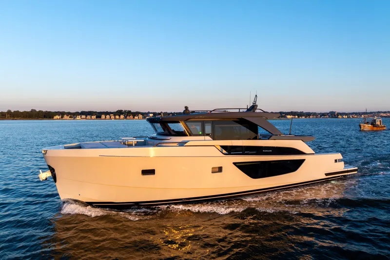 Slide: The Image of 2024 Bluegame BGX63 yacht cruising on calm waters at sunset. - 0
