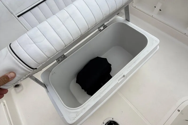 Slide: The Image of Open storage compartment on 2016 Bayliner Element F18 boat with white cushioned seat. - 14