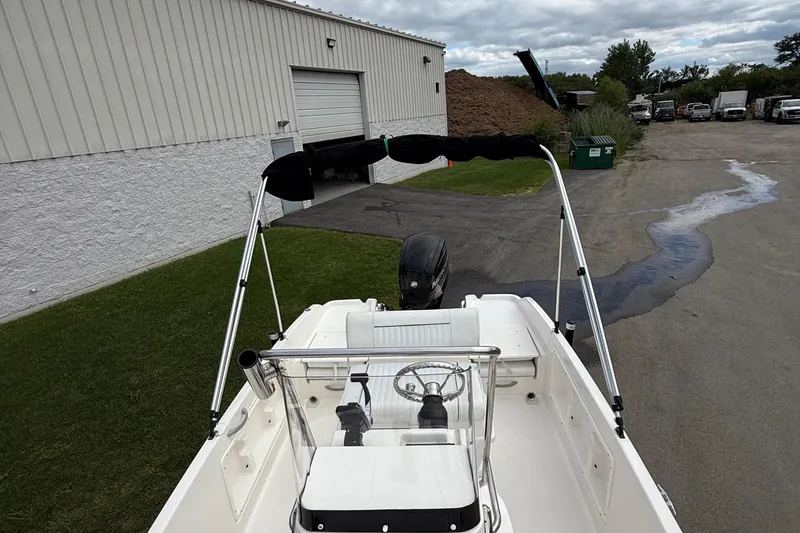 Slide: The Image of 2016 Bayliner Element F18 boat with bimini top, parked near industrial building. - 16