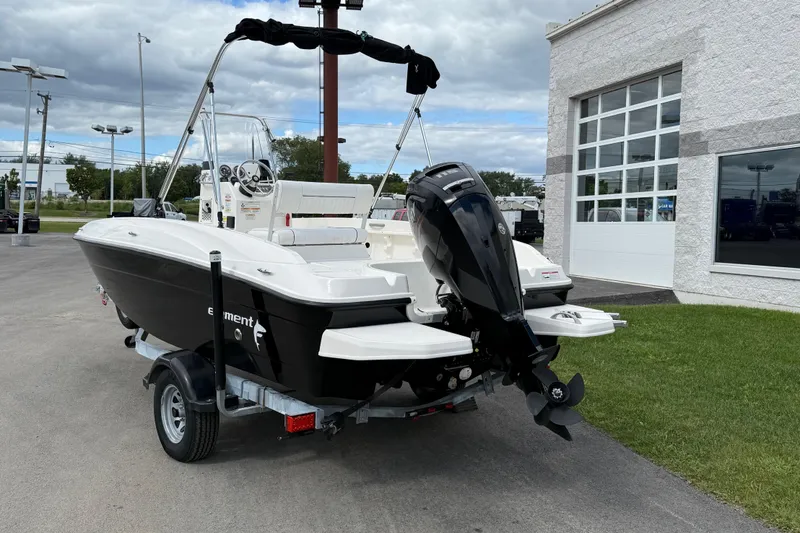 Slide: The Image of 2016 Bayliner Element F18 boat on trailer, parked near a building. - 2