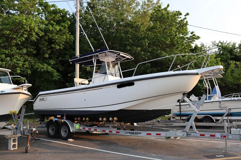 The Image of 2001 Boston Whaler 260 Outrage boat on trailer, parked outdoors. - 0