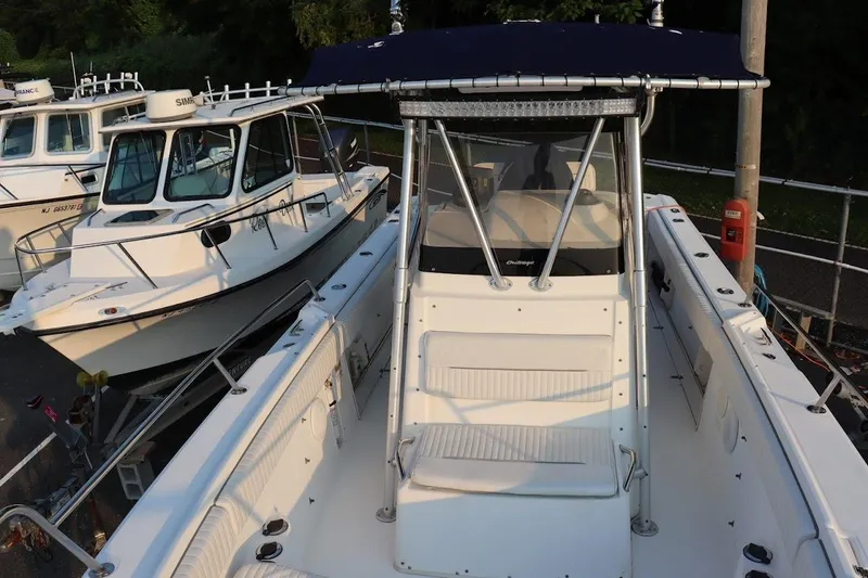 Slide: The Image of 2001 Boston Whaler 260 Outrage boat with center console and seating, docked alongside another vessel. - 32