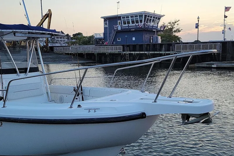 Slide: The Image of 2001 Boston Whaler 260 Outrage boat docked near a waterfront building at sunset. - 33