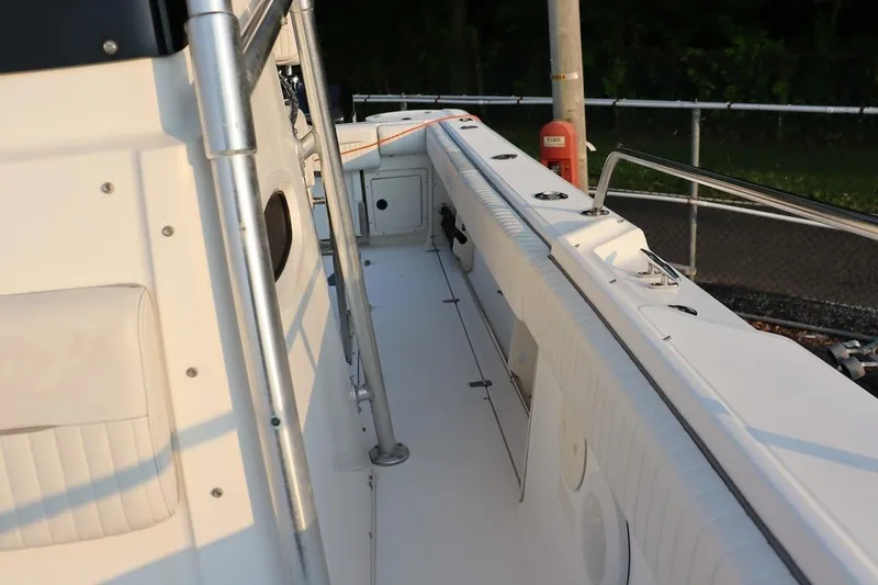 Slide: The Image of 2001 Boston Whaler 260 Outrage boat deck with railing and seating, docked outdoors. - 7