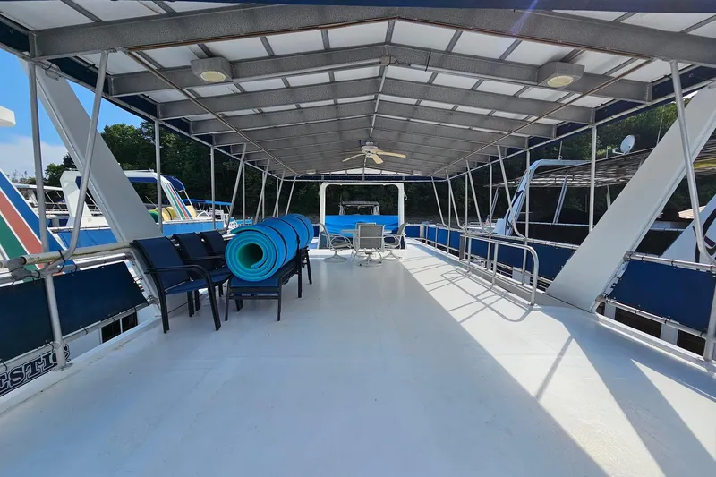 Slide: The Image of 2002 Jamestowner houseboat deck with chairs, blue mats, and canopy. - 10