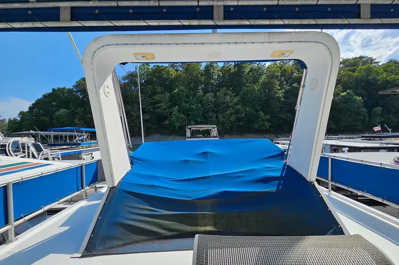 Slide: The Image of 2002 Jamestowner houseboat with blue canopy, docked near lush green trees. - 11