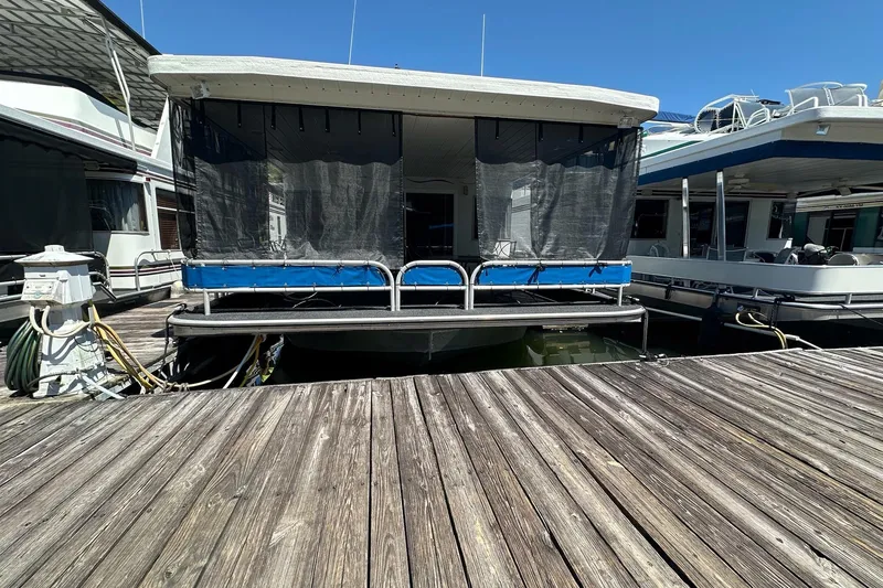 Slide: The Image of 2002 Jamestowner houseboat docked at marina, featuring screened porch and wooden deck. - 2