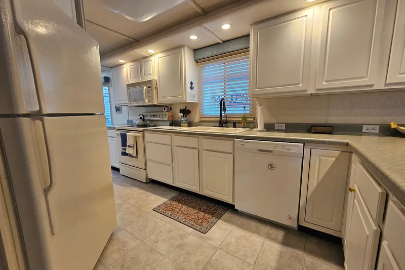 Slide: The Image of Modern kitchen interior on a 2002 Jamestowner houseboat with white cabinets and appliances. - 24