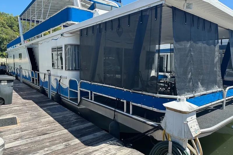 Slide: The Image of 2002 Jamestowner houseboat docked, featuring blue accents and screened porch area. - 3