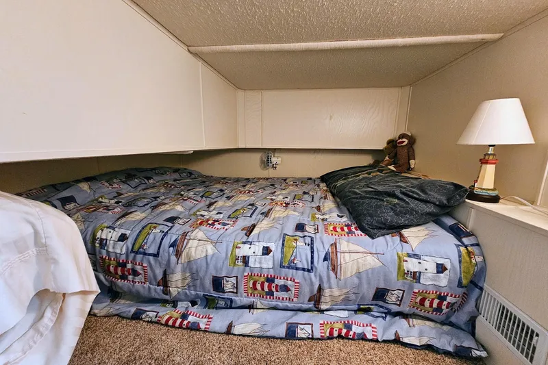 Slide: The Image of Cozy 2002 Jamestowner houseboat bedroom with nautical-themed bedding and a bedside lamp. - 35