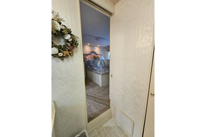 Slide: The Image of Interior view of a 2002 Jamestowner houseboat bedroom with cozy decor and floral wreath. - 48