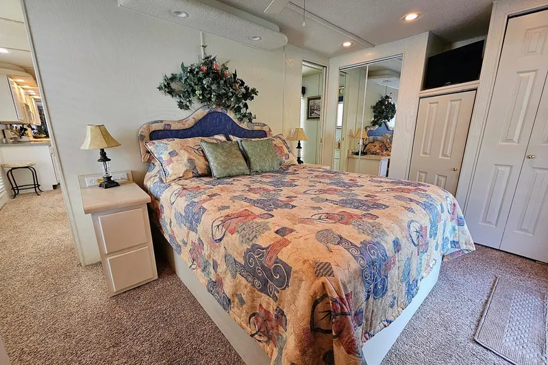 Slide: The Image of Cozy bedroom in a 2002 Jamestowner houseboat with floral decor and mirrored closet. - 49
